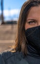 Hispanic woman with brown eyes wearing a mask and posing with a serious face expression