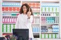 Hispanic woman with curly hair working at pharmacy drugstore showing middle finger, impolite and rude fuck off expression Royalty Free Stock Photo