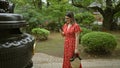 Hispanic woman in glasses captures japan\'s ancient gotokuji temple beauty with her phone, enjoying her role as a tourist