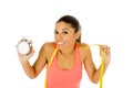 Hispanic woman holding alarm clock and taylor measure tape in time for sport and diet concept Royalty Free Stock Photo