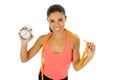 Hispanic woman holding alarm clock and taylor measure tape in time for sport and diet concept Royalty Free Stock Photo