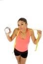 Hispanic woman holding alarm clock and taylor measure tape in time for sport and diet concept Royalty Free Stock Photo
