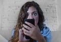 Hispanic woman holding mobile phone in crazy eyes social network and internet addiction concept Royalty Free Stock Photo