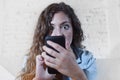 Hispanic woman holding mobile phone in crazy eyes social network and internet addiction concept Royalty Free Stock Photo