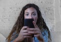 Hispanic woman holding mobile phone in crazy eyes social network and internet addiction concept Royalty Free Stock Photo