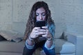 Hispanic woman holding mobile phone in crazy eyes social network and internet addiction concept Royalty Free Stock Photo