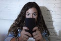 Hispanic woman holding mobile phone in crazy eyes social network and internet addiction concept Royalty Free Stock Photo