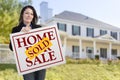 Hispanic Woman Holding Sold Home Sale Sign in Front of House Royalty Free Stock Photo