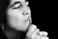 Hispanic woman kissing a small crucifix Royalty Free Stock Photo