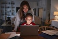 Hispanic woman looking over her sonÃ¯Â¿Â½s shoulder while he does his homework using laptop computer Royalty Free Stock Photo