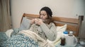 Hispanic woman lying alone in her bed well wrapped up, sick with the flu, drinking a cup of tea Royalty Free Stock Photo