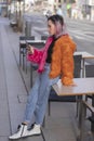 Hispanic woman with pink hair wearing a fluffy jacket with jeans and using her phone outdoors Royalty Free Stock Photo