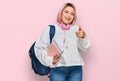 Hispanic woman with pink hair wearing student backpack and headphones pointing fingers to camera with happy and funny face Royalty Free Stock Photo