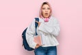 Hispanic woman with pink hair wearing student backpack and headphones surprised pointing with finger to the side, open mouth Royalty Free Stock Photo