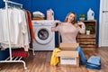 Hispanic woman putting clothes in donation box looking confident with smile on face, pointing oneself with fingers proud and happy Royalty Free Stock Photo