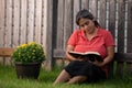 Hispanic Woman Reading Her Bible by Flower Pot Royalty Free Stock Photo
