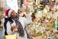 Hispanic woman in Santa hat choosing decorations at street Christmas fair Royalty Free Stock Photo