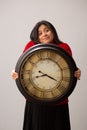 Hispanic Woman Shrugs While Holding Clock In Front Of Her