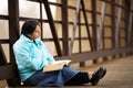 Hispanic Woman Sitting On A Bridge And Reading Bible Royalty Free Stock Photo