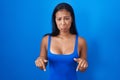 Hispanic woman standing over blue background pointing down looking sad and upset, indicating direction with fingers, unhappy and Royalty Free Stock Photo