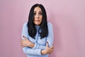 Hispanic woman standing over pink background shaking and freezing for winter cold with sad and shock expression on face Royalty Free Stock Photo