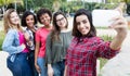 Hispanic woman taking selfie with group of international girlfriends