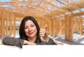 Hispanic Woman With Thumbs Up On Site Inside New Home Construction Framing.