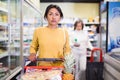 Hispanic woman walking with shopping trolley in grocery shop Royalty Free Stock Photo