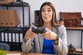 Hispanic woman working at the office playing video games making fish face with mouth and squinting eyes, crazy and comical