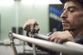 Hispanic worker sanding a bicycle frame at his workshop