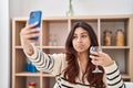 Hispanic young business woman taking a selfie picture drinking a glass of wine depressed and worry for distress, crying angry and Royalty Free Stock Photo