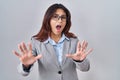 Hispanic young business woman wearing glasses afraid and terrified with fear expression stop gesture with hands, shouting in shock Royalty Free Stock Photo
