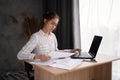 hispanic young business woman working with documents using laptop in home office, analyzing work results, doing Royalty Free Stock Photo