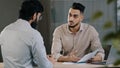 Hispanic young businessman man financial advisor agent lawyer worker consulting unknown male client customer explaining Royalty Free Stock Photo