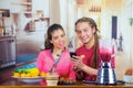 Hispanic young healthy couple enjoying breakfast together, sharing fruits, drinking smoothie and smiling, home kitchen Royalty Free Stock Photo