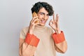 Hispanic young man having conversation talking on the smartphone doing ok sign with fingers, smiling friendly gesturing excellent Royalty Free Stock Photo