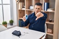 Hispanic young man holding glucometer device with angry face, negative sign showing dislike with thumbs down, rejection concept