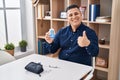 Hispanic young man holding glucometer device smiling happy and positive, thumb up doing excellent and approval sign