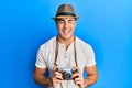 Hispanic young man holding vintage camera smiling and laughing hard out loud because funny crazy joke Royalty Free Stock Photo