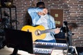 Hispanic young man playing classic guitar at music studio smiling cheerful playing peek a boo with hands showing face Royalty Free Stock Photo