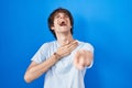 Hispanic young man standing over blue background laughing at you, pointing finger to the camera with hand over body, shame Royalty Free Stock Photo