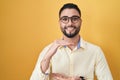 Hispanic young man wearing business clothes and glasses gesturing with hands showing big and large size sign, measure symbol Royalty Free Stock Photo