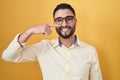 Hispanic young man wearing business clothes and glasses pointing with hand finger to face and nose, smiling cheerful Royalty Free Stock Photo