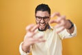 Hispanic young man wearing business clothes and glasses shouting frustrated with rage, hands trying to strangle, yelling mad Royalty Free Stock Photo