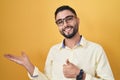 Hispanic young man wearing business clothes and glasses showing palm hand and doing ok gesture with thumbs up, smiling happy and Royalty Free Stock Photo