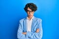 Hispanic young man wearing business jacket and glasses skeptic and nervous, disapproving expression on face with crossed arms Royalty Free Stock Photo