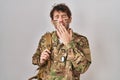 Hispanic young man wearing camouflage army uniform bored yawning tired covering mouth with hand Royalty Free Stock Photo