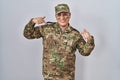 Hispanic young man wearing camouflage army uniform looking confident with smile on face, pointing oneself with fingers proud and Royalty Free Stock Photo