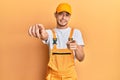 Hispanic young man wearing handyman uniform pointing to you and the camera with fingers, smiling positive and cheerful Royalty Free Stock Photo