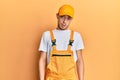 Hispanic young man wearing handyman uniform in shock face, looking skeptical and sarcastic, surprised with open mouth Royalty Free Stock Photo